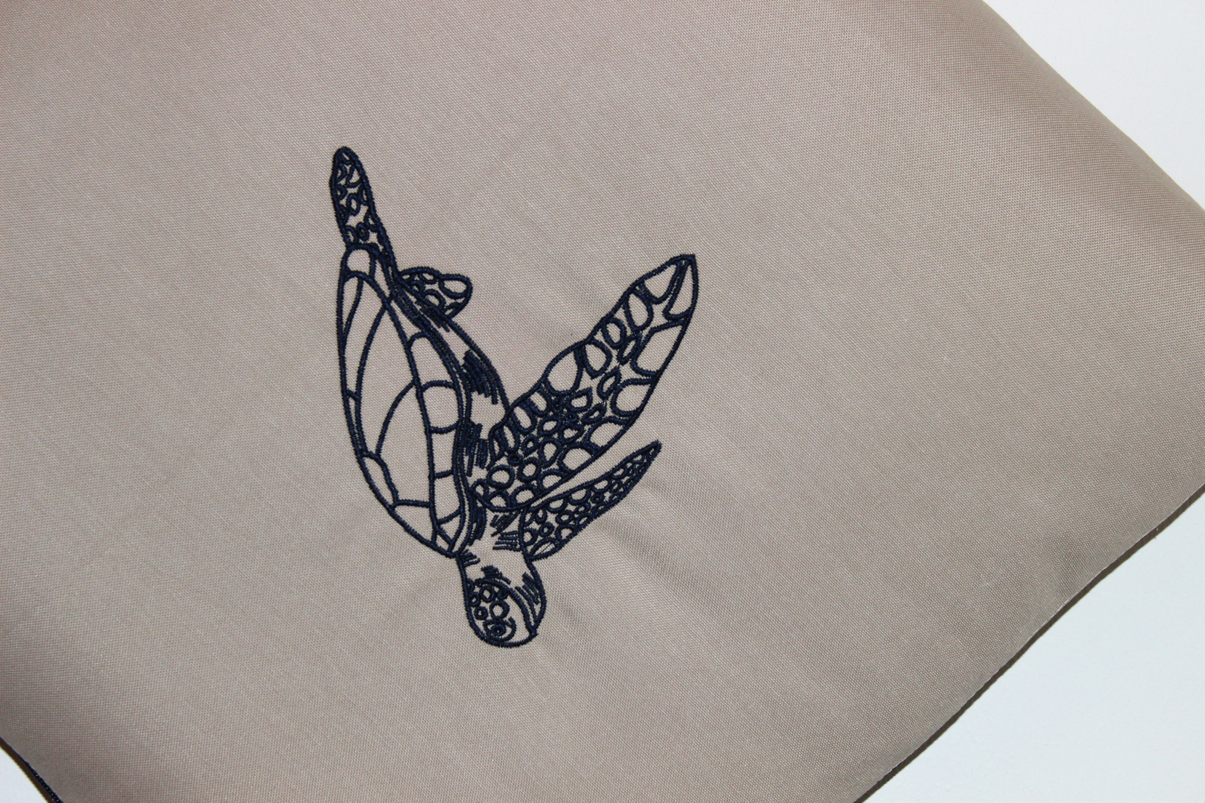 Close-up of turtle embroidery on Mecks 2 in 1 cushion blanket fabric