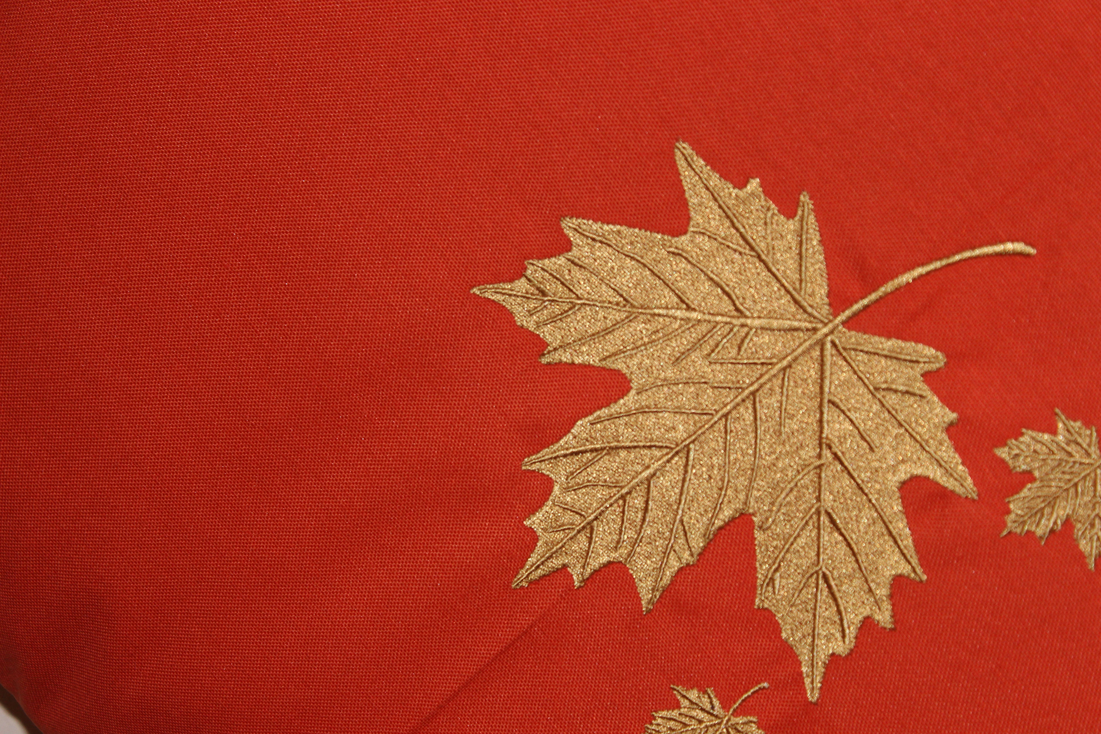 Gold maple leaf design on a red fabric background